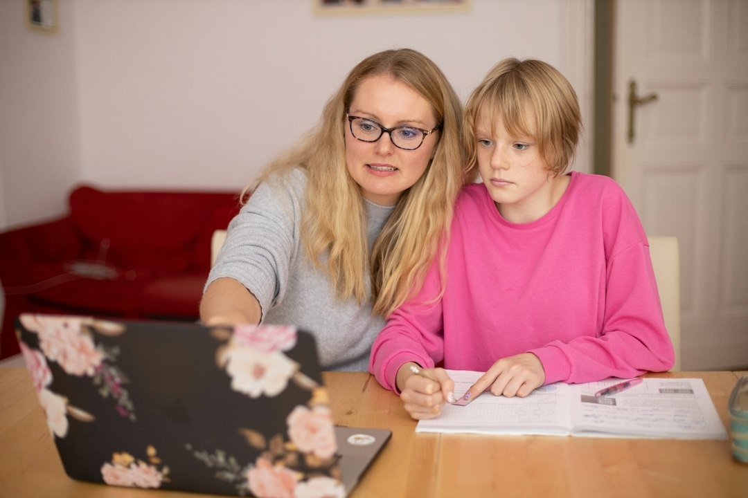 Woman and child learn together at a laptop and notebook.